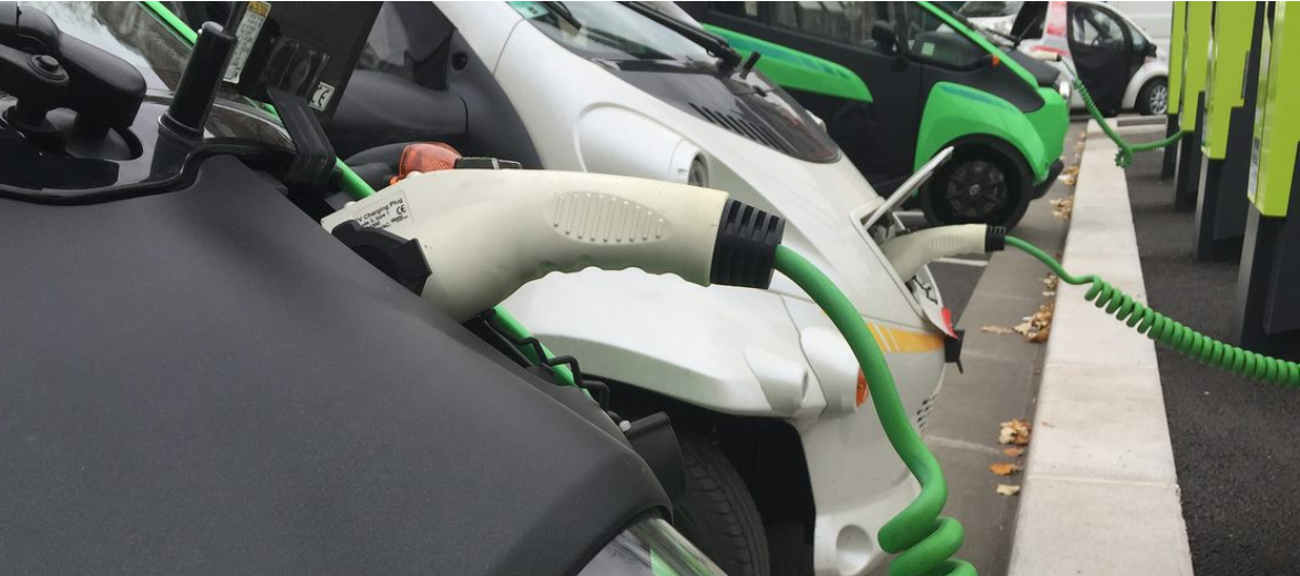 Row of electric vehicles plugged into charging stations